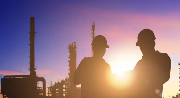 Engineer and foreman working at a petrochemical refinery at sunrise