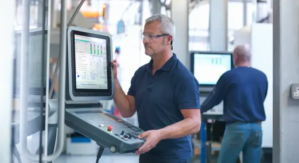 Engineers at lathe controls in a factory